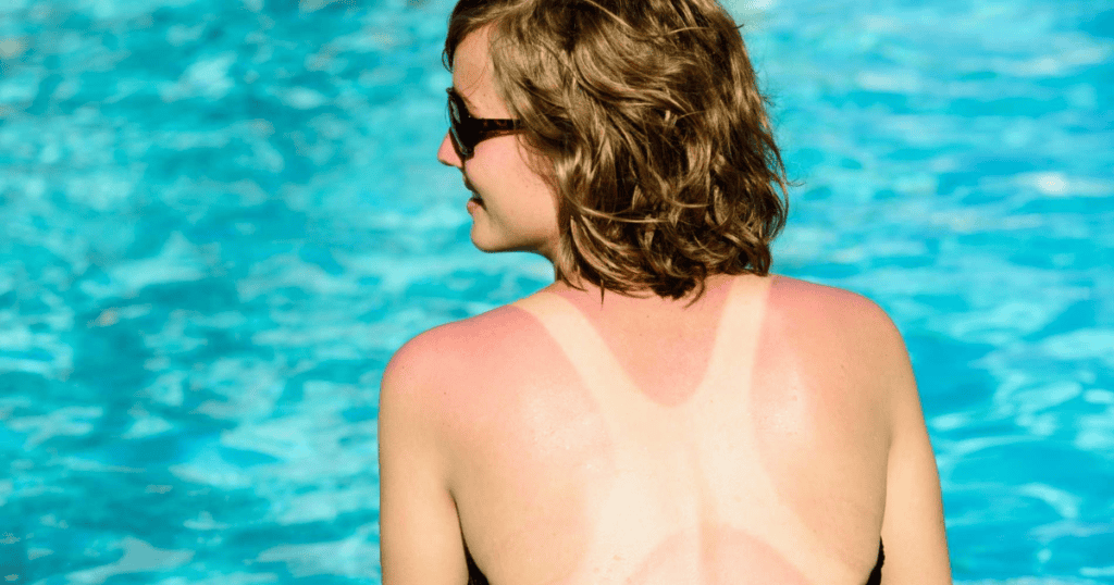 Mujer con gafas de sol en piscina, vista de espaldas, agua azul clara de fondo.