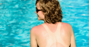 Mujer con gafas de sol en piscina, vista de espaldas, agua azul clara de fondo.