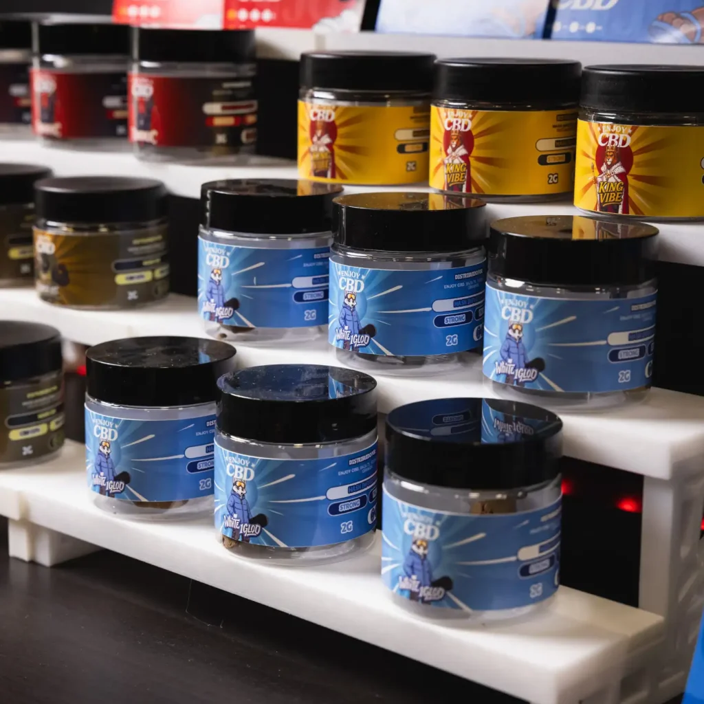 Envases de 30g de productos de CBD en diferentes colores y sabores en estantería.
